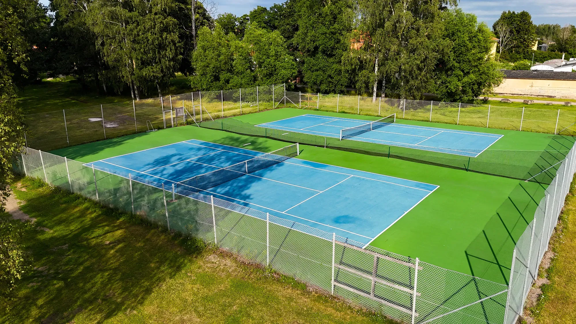 Två tennisbanor omgivna av grönska.